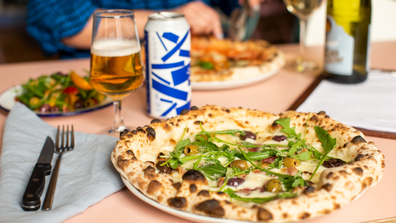 Plates of woodfired pizza with a glass of beer on the table at Grumpys