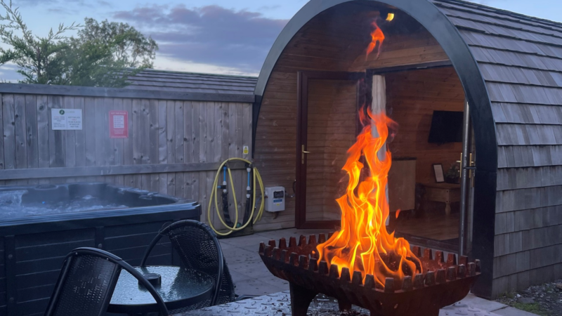 A fire pit and hot tub outside of a glamping pod at Lady Heyes Holiday Park
